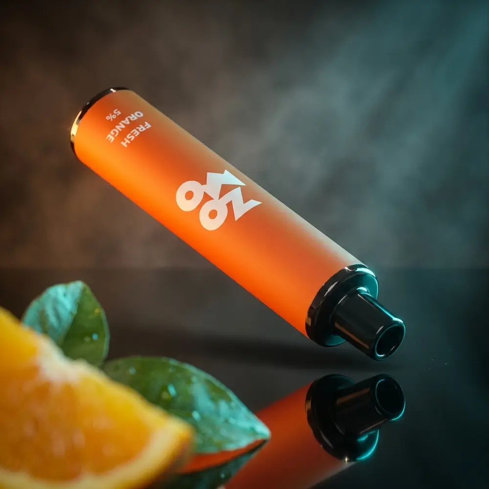Pod descartavel Zomo Flow Fresh Orange suspenso sobre acrilico preto, reflexos e fatia de laranja em primeiro plano - Vapor Gringo