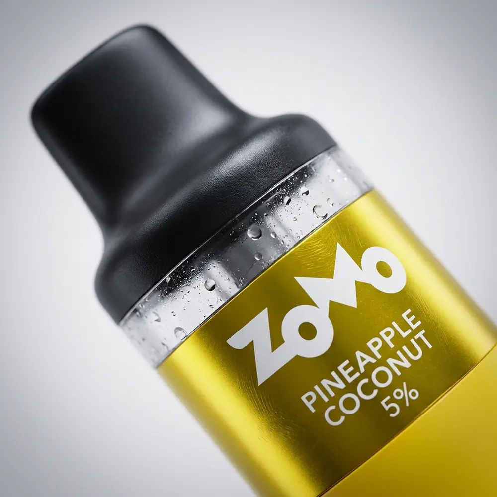 Close-up do Pod Descartável Zomo Flow Pineapple Coconut mostrando logotipo, banda metálica, gotas de condensação e textura plástica - Vapor Gringo