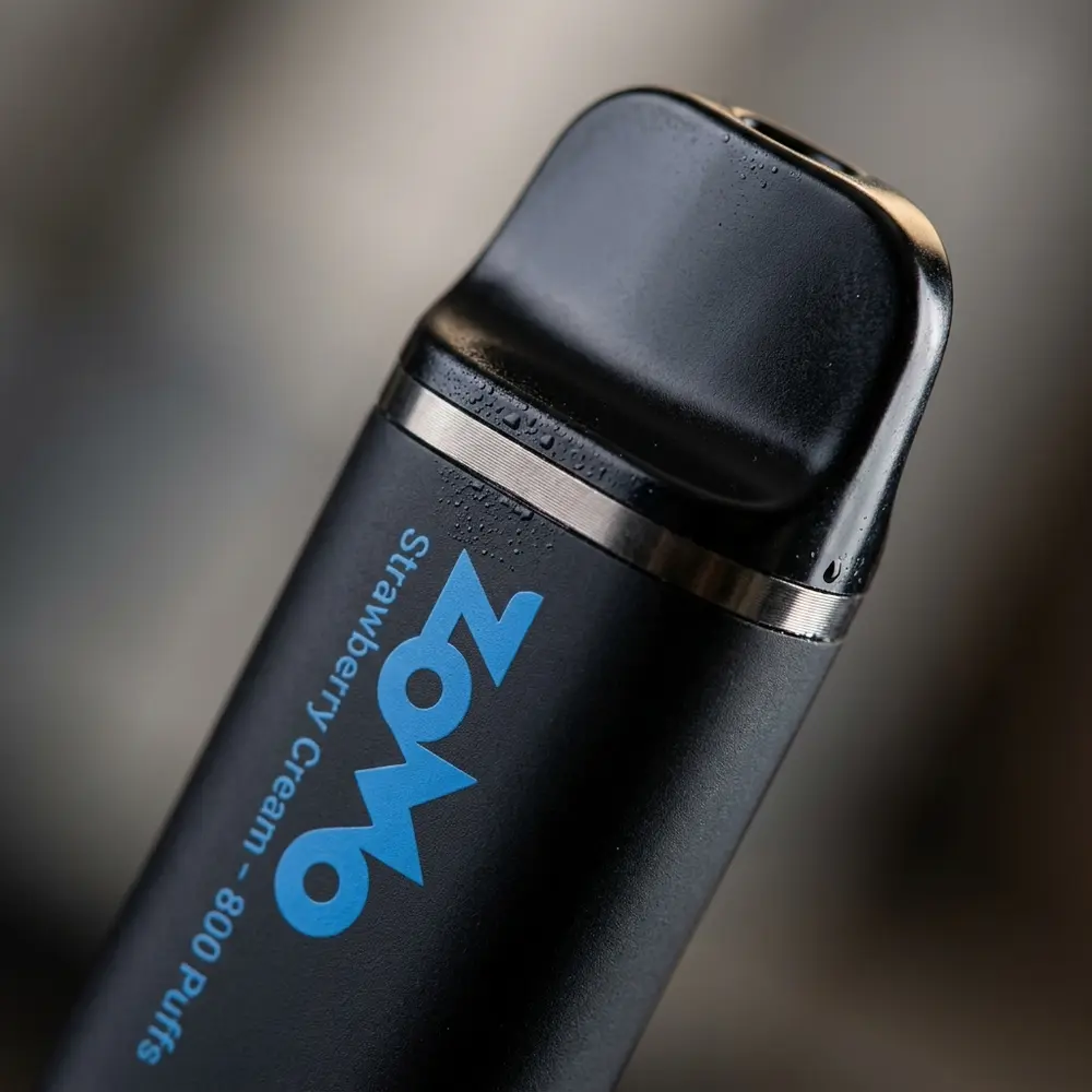 Detalhe do bocal e do rótulo do Pod Zomo Strawberry Cream 800 puffs com gotas de condensação e reflexos - Vapor Gringo