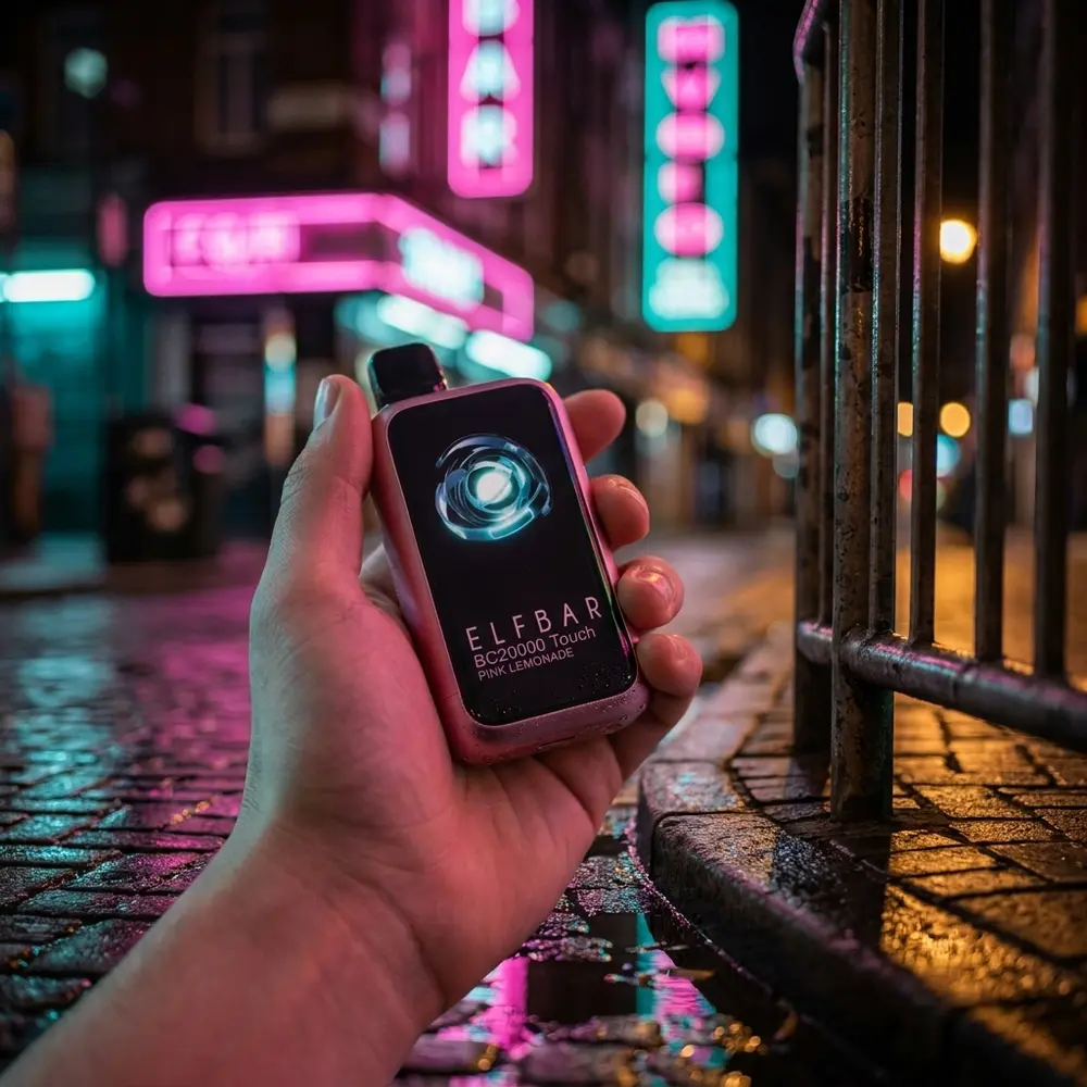Pod Descartável Elf Bar BC20000 Pink Lemonade na mão de um jovem em rua urbana molhada com luzes neon ao fundo - Vapor Gringo