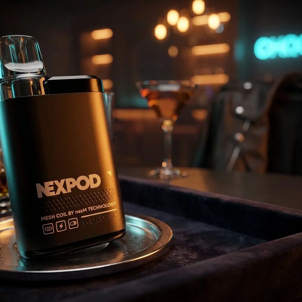 Pod Recarregável NexPod Tropical Ice apoiado em bandeja de couro em lounge, copo de coquetel e luzes quentes ao fundo - Vapor Gringo