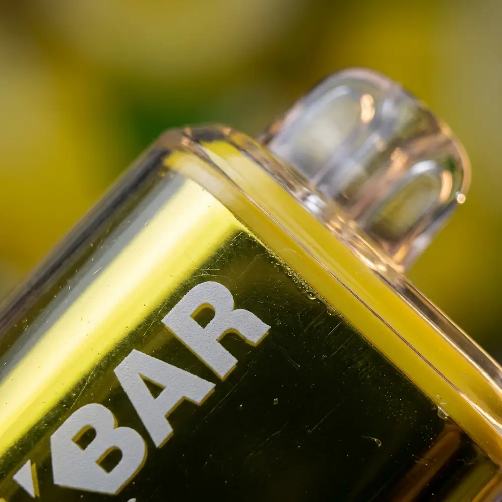 Detalhe macro do NikBar Sour Lemon Drops mostrando bocal translúcido, rotulo e goticulas de condensacao - Vapor Gringo