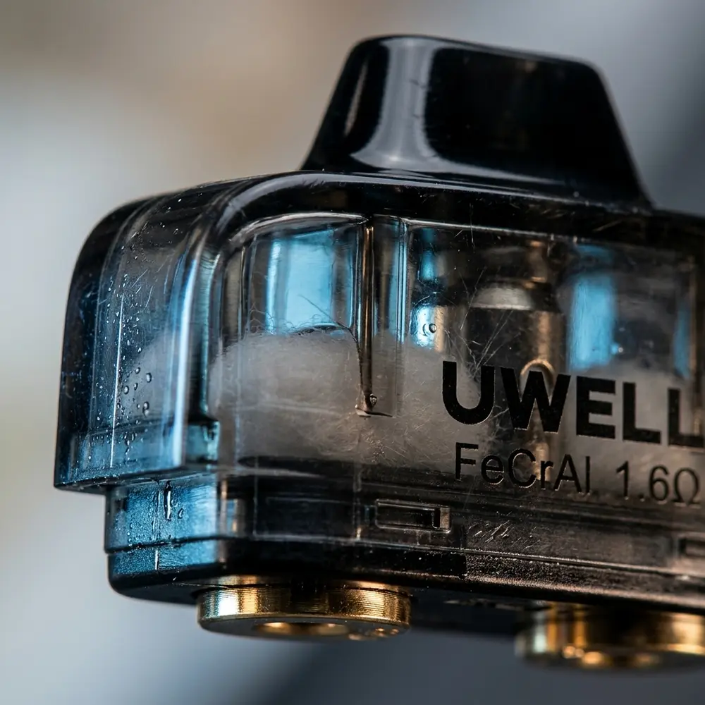 Macro do cartucho Amulet 1.6Ω Uwell mostrando boca, contatos metálicos e condensação na carcaça transparente - Vapor Gringo