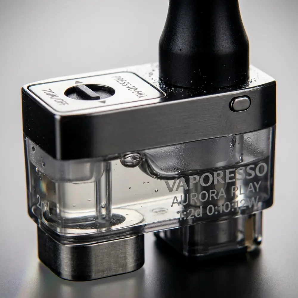 Close-up do pod Aurora Play 2ml mostrando boca, contatos metalicos, transparência e gotas de condensacao - Vapor Gringo