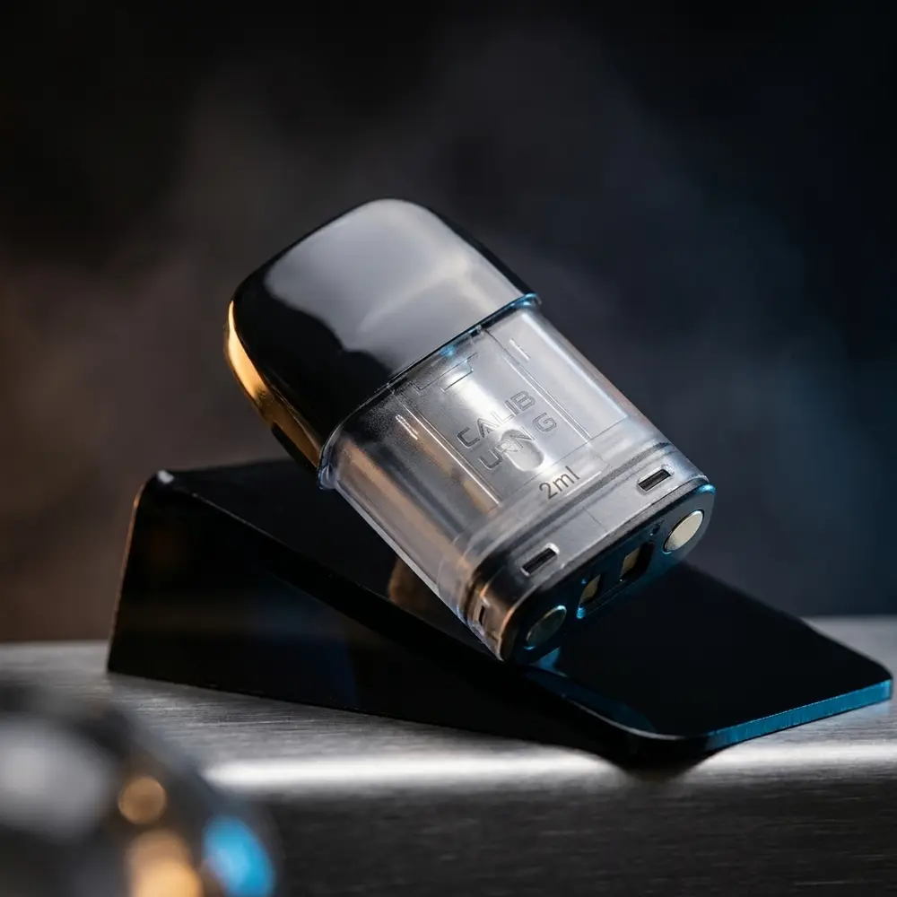 Pod de reposição Uwell Caliburn G apoiado em acrílico preto com reflexos quentes e detalhes metálicos visíveis - Vapor Gringo