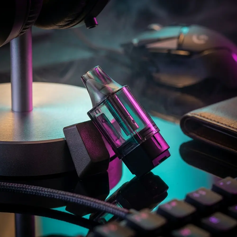 Pod Reposição Caliburn Ironfist L Uwell em bancada gamer RGB apoiado em keycap com reflexos coloridos - Vapor Gringo