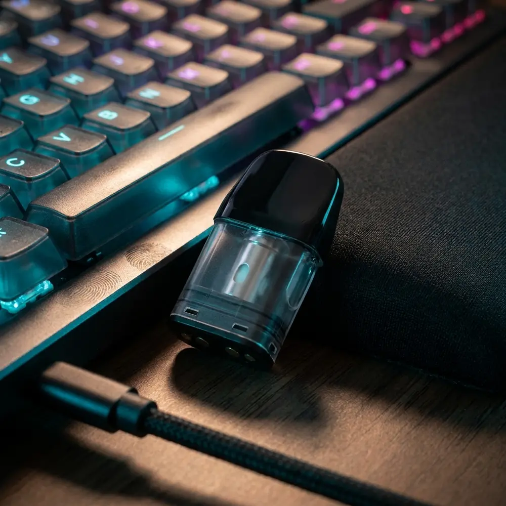 Pod reposicao Caliburn Uwell apoiado perto de teclado RGB em setup gamer com reflexos neon - Vapor Gringo