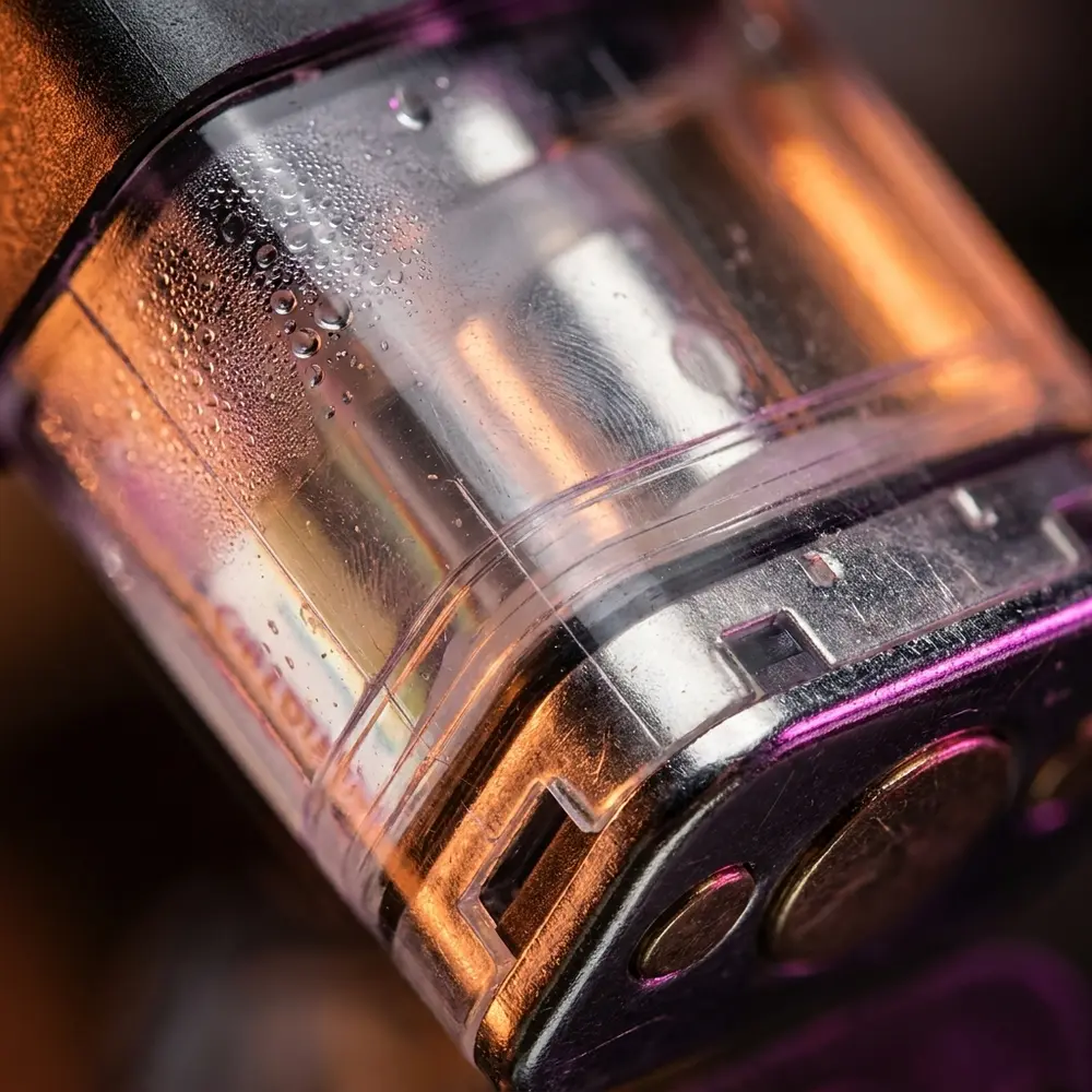 Macro do pod reposicao Hawaiian Pog mostrando conector metalico, corpo transparente com gotas minimas e reflexos precisos - Vapor Gringo
