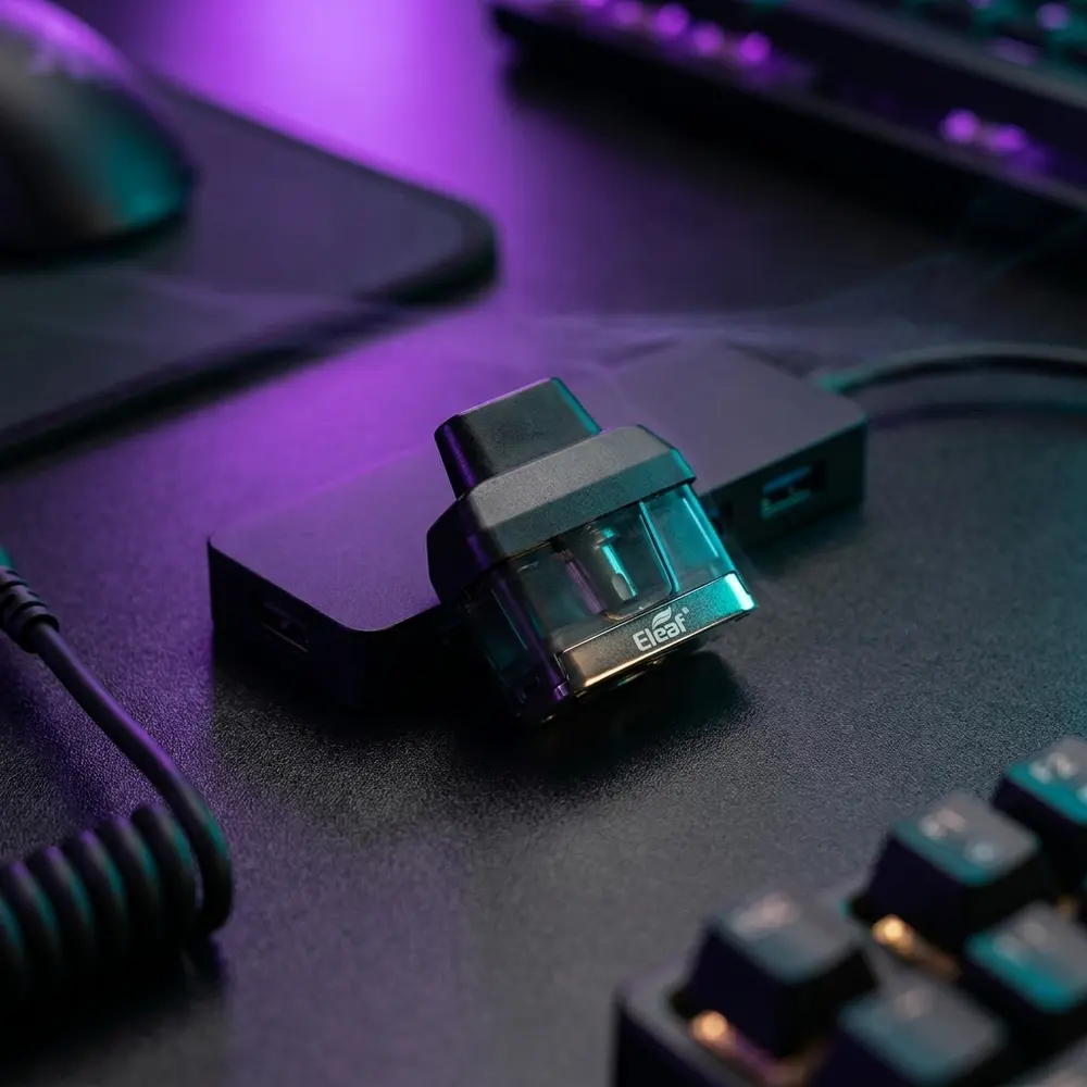Pod reposicao Icare 2 Eleaf apoiado em mesa gamer RGB com teclado e luzes roxas e teal ao fundo - Vapor Gringo