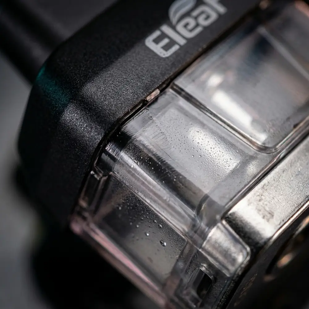 Close-up da junçao transparente e metal do pod Icare 2 Eleaf com gotas de condensacao e reflexos - Vapor Gringo