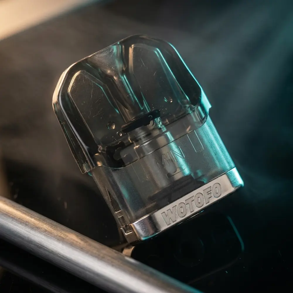 Pod Reposicao Manik Mini 3ml apoiado em superficie acrilica brilhante com luzes neon sutis e reflexos - Vapor Gringo