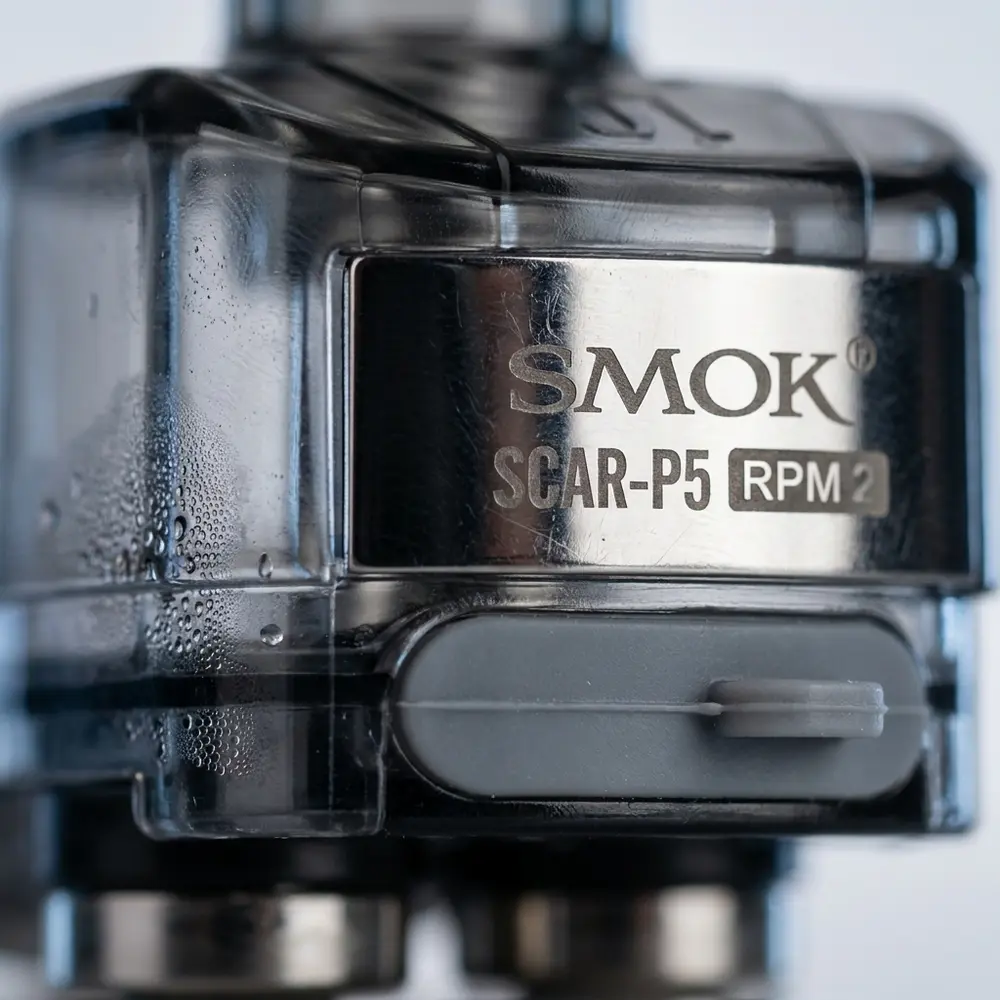 Detalhe do Pod Reposição Scar P5 RPM 2 da Smok mostrando casco transparente, banda metálica e gotas de condensação - Vapor Gringo