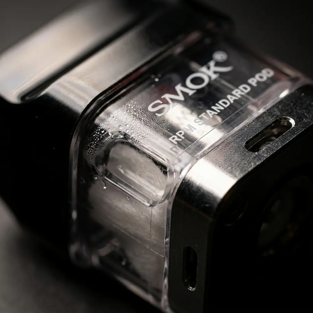 Macro do Pod Reposição Standard RPM40 SMOK mostrando conector metálico, cápsula transparente e gotas de condensação - Vapor Gringo