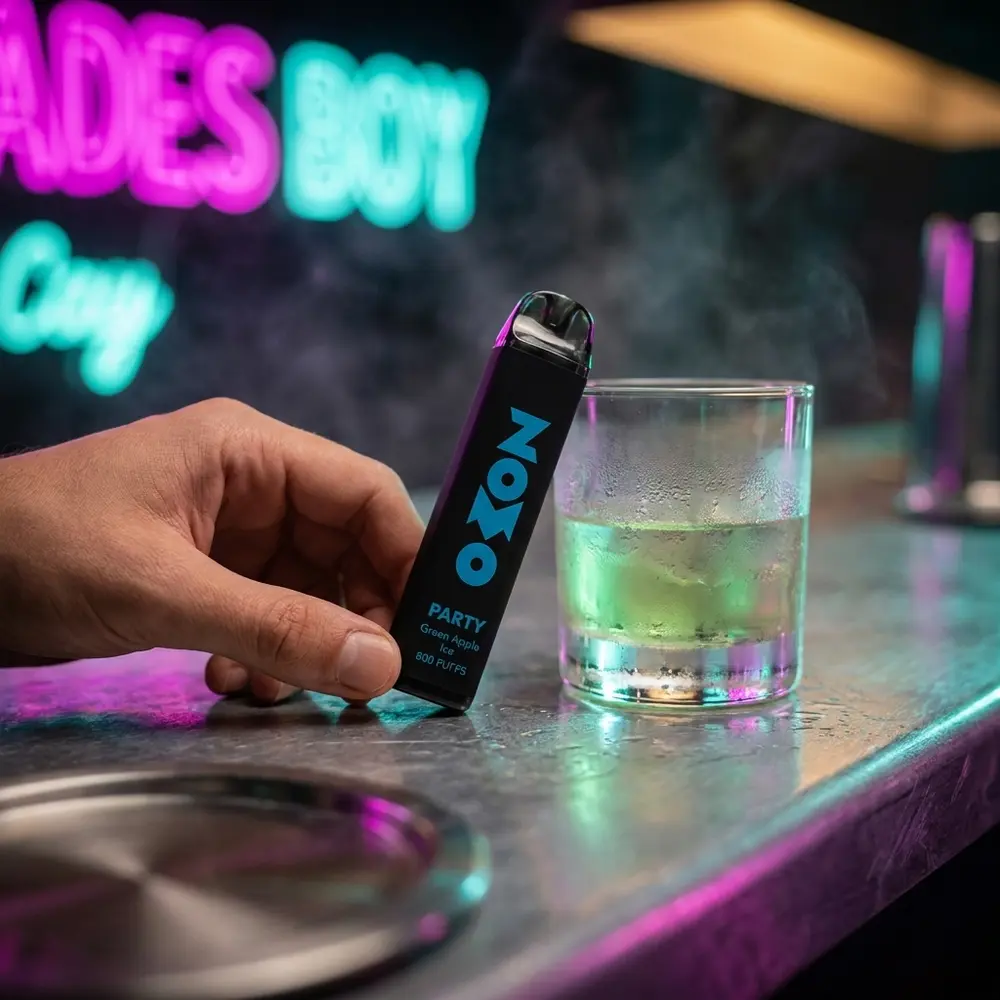 Pod Zomo Party Green Apple Ice apoiado em balcão metálico com reflexos neon urbanos e copo ao lado - Vapor Gringo