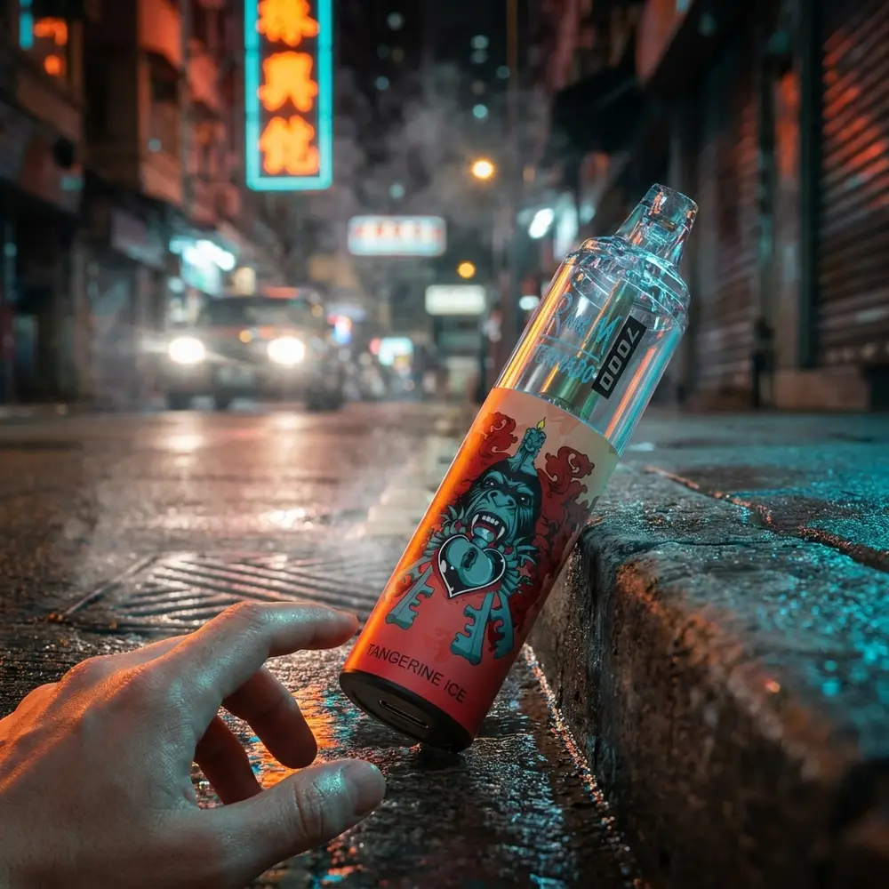 Rand M Tornado Tangerine Ice apoiado em guia molhada de rua com reflexos neon laranja e azul e uma mao alcançando - Vapor Gringo