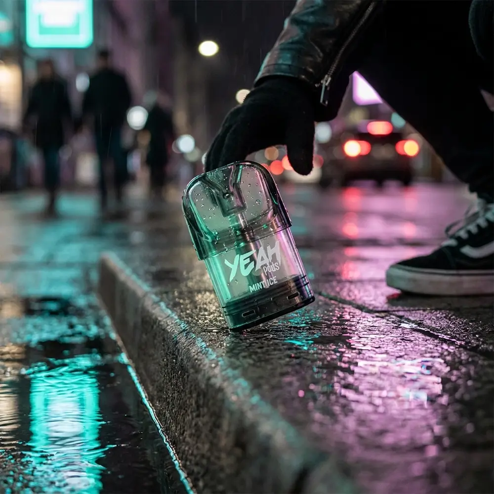 Refil para Pod Juul Yeah Mint Ice apoiado em beira molhada na rua, reflexos neon azuis e magenta ao fundo - Vapor Gringo