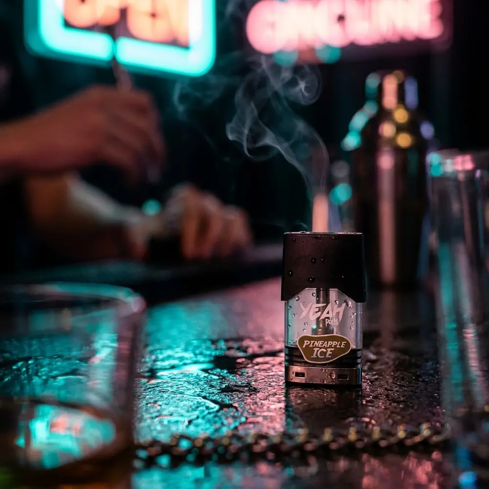 Refil para Pod Yeah Pineapple ICE apoiado em balcão molhado com luzes neon desfocadas ao fundo - Vapor Gringo