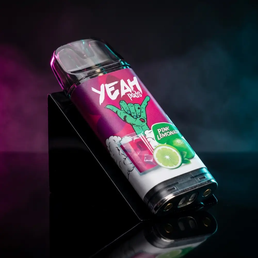 Refil para Pod Juul Yeah Pink Lemonade em close sobre base acrílica preta com iluminação rosa e ciano, rótulo legível - Vapor Gringo