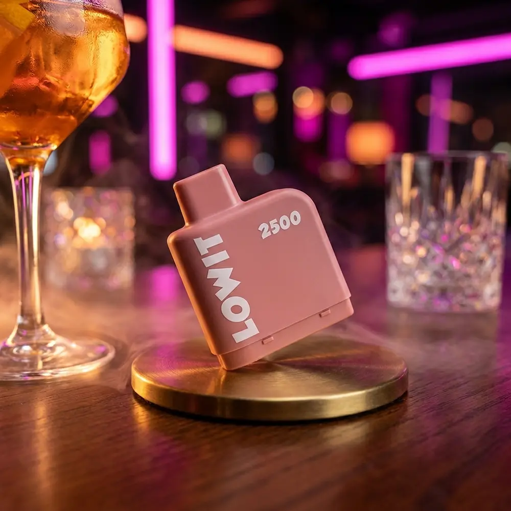 Refil Pod Lowit 2500 Puffs Juicy Peach da Elf Bar encostado em balcão de bar noturno com luzes neon e copo desfocado. - Vapor Gringo