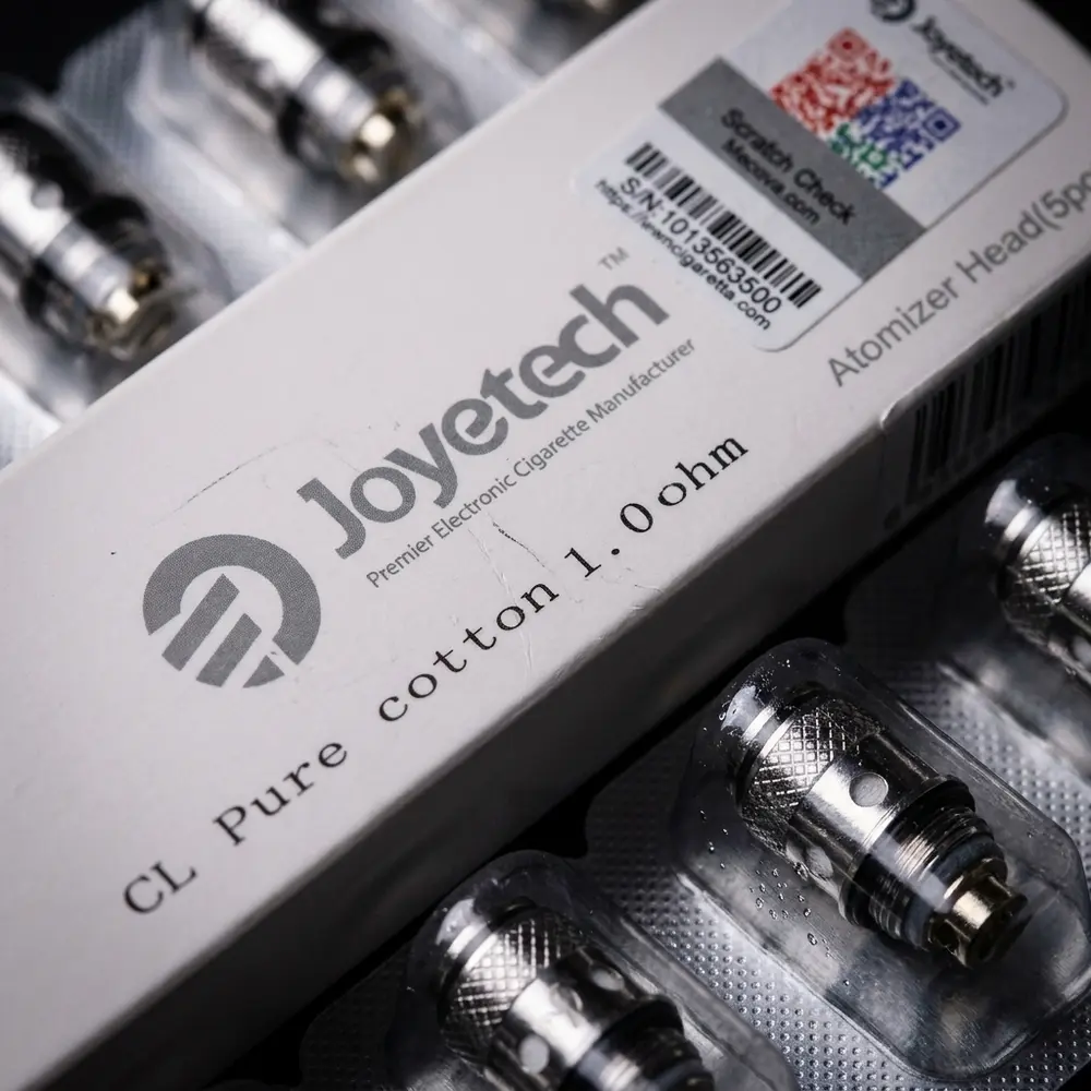 Detalhe macro da resistencia Coil eGo One Joyetech mostrando textura metalica, algodao e goticulas - Vapor Gringo
