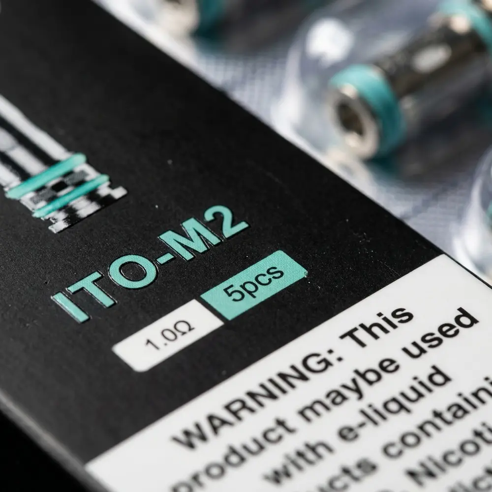 Macro da etiqueta e textura da Resistência Coil ITO Voopoo, detalhe de tipografia, verniz e microreflexos - Vapor Gringo