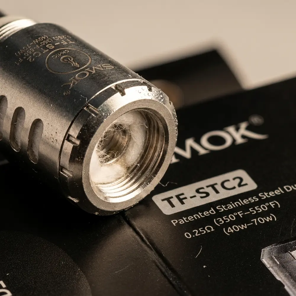 Macro da Resistência Coil TF-STC2/TF-Ti da Smok mostrando acabamento metálico, fibras de algodão e gravação do logo em close - Vapor Gringo