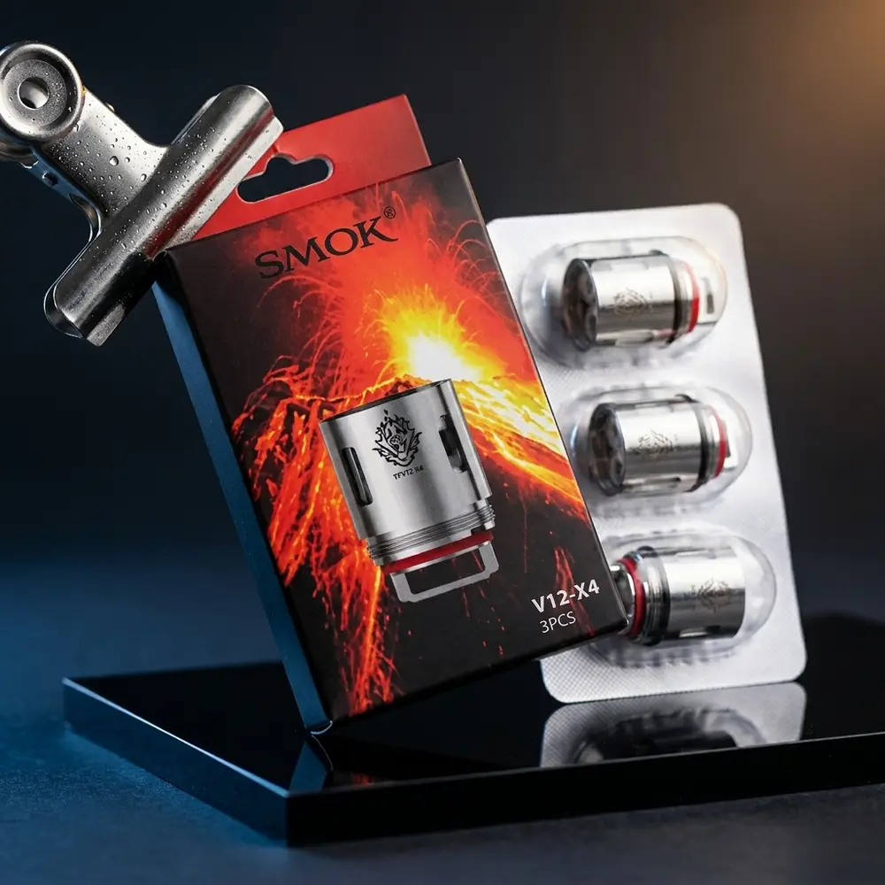 Pack da Resistência Coil TFV12 X4 0.15ohm Smok inclinado sobre acrílico preto, reflexos metálicos e iluminação contrastada - Vapor Gringo