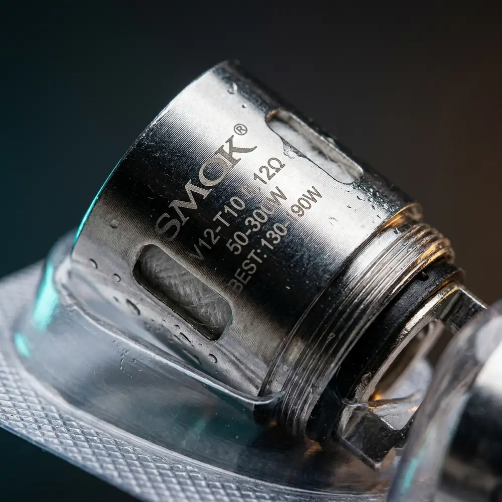 Detalhe da Resistencia Coil TFV8 T10 Smok mostrando metal, texturas, gravacoes e gotas de condensacao - Vapor Gringo