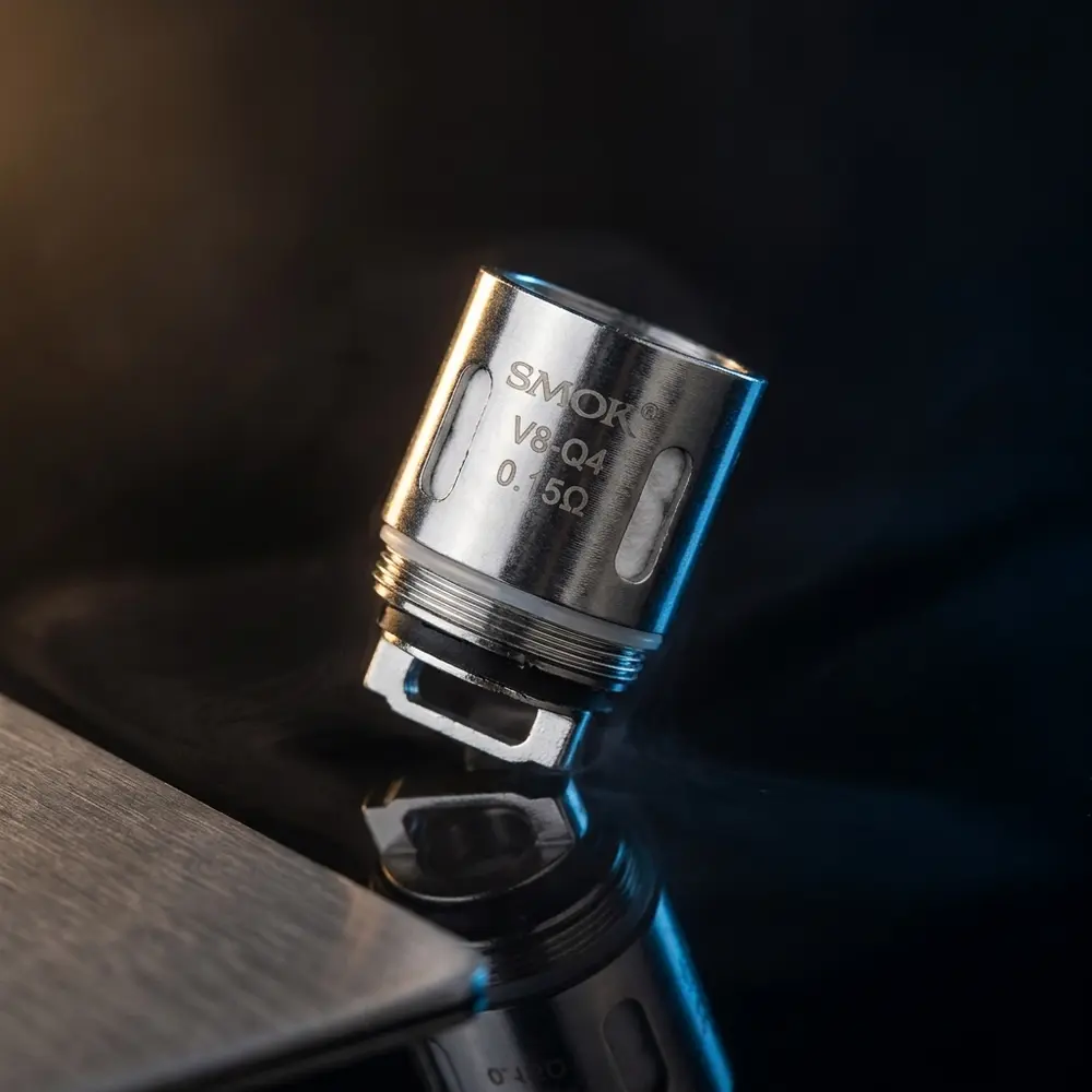 Resistência Coil V8 Q4 0.15Ω da Smok sobre placa acrílica preta com reflexos metálicos e luzes dramáticas - Vapor Gringo