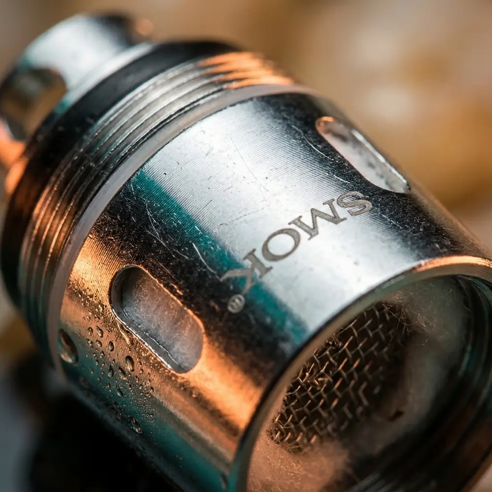Detalhe macro da Resistência Coil V8 Q4 0.15Ω da Smok mostrando metal, rosca, textura e gotas de condensação - Vapor Gringo