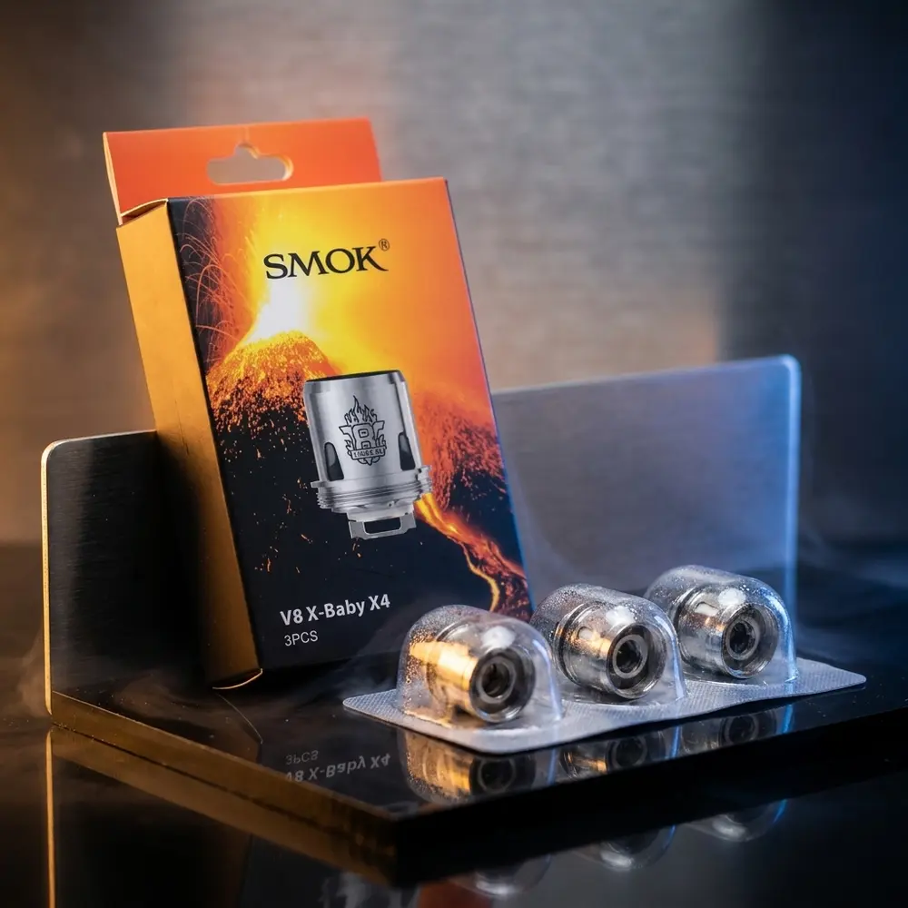 Resistência Coil V8 X-Baby Q2 0.4ohm Smok sobre acrílico preto com luzes azul e âmbar, embalagem visível - Vapor Gringo