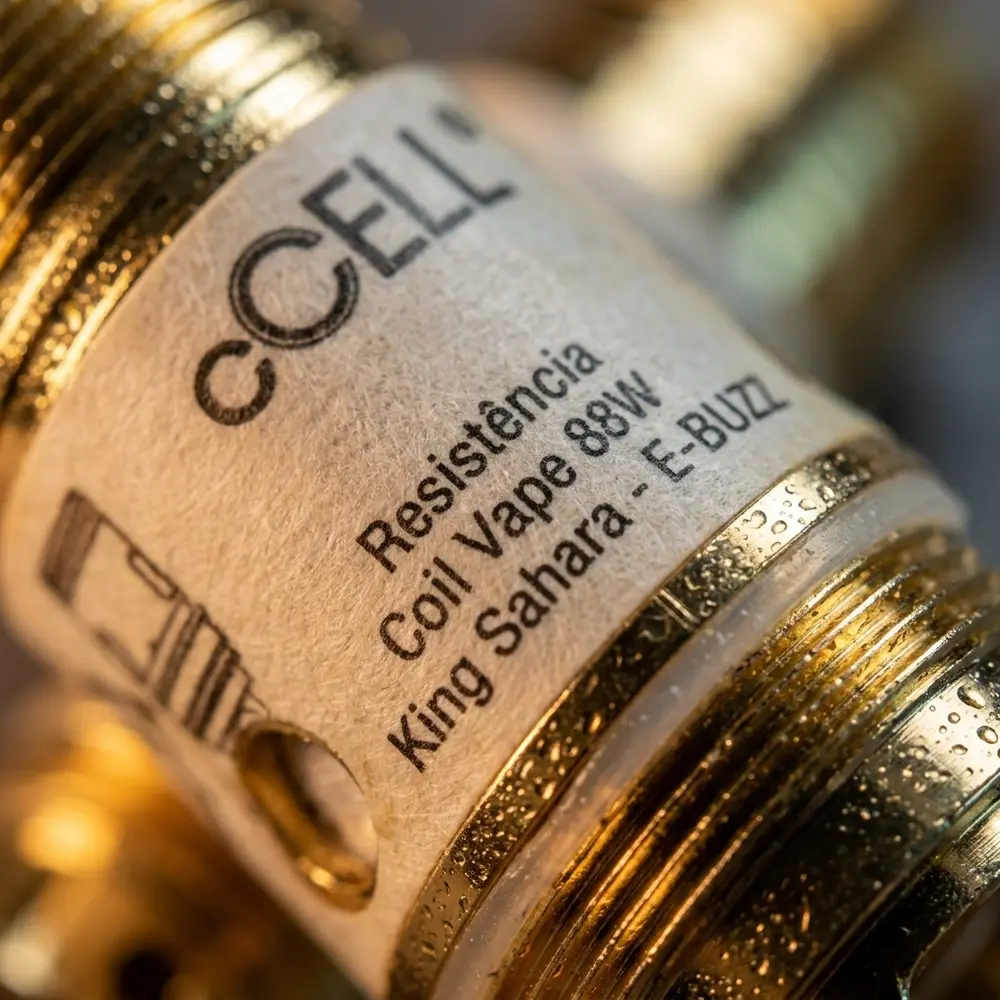 Macro da etiqueta e crimpagem da Resistência Coil Vape 88W King Sahara E-BUZZ com gotas de condensação e textura metálica - Vapor Gringo