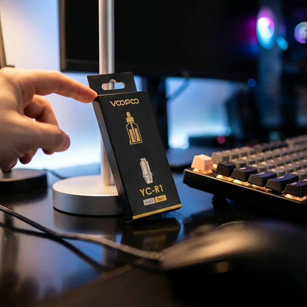 Pack Resistência Coil YC-R1 Voopoo apoiado em mesa gamer RGB entre teclado e fones, luzes neon ao fundo - Vapor Gringo