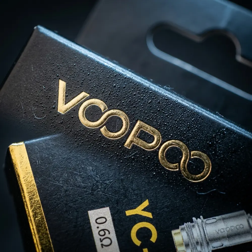 Detalhe macro do logotipo e textura da embalagem Resistência Coil YC-R1 Voopoo com gotas de condensação - Vapor Gringo