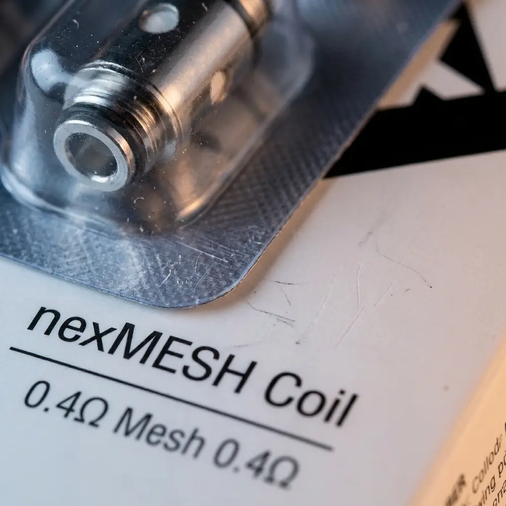Detalhe da Resistência nexMesh 0.4Ohm MTL mostrando logo, tipografia e textura metálica brilhante - Vapor Gringo