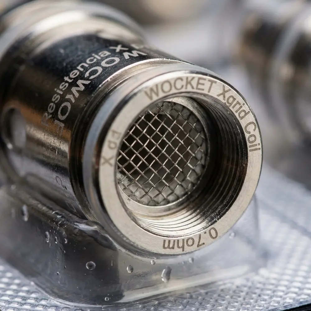 Close da malha X-Grid da resistencia 0.7ohm Wocket SnowWolf mostrando textura metalica e gotas de condensacao - Vapor Gringo