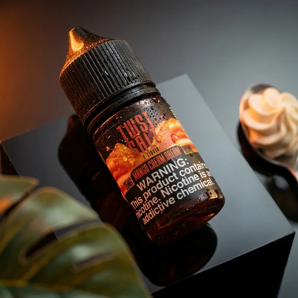 Garrafa Twst Mango Cream Dream 30ml sobre acrilico preto com iluminacao laranja cremosa e gotas de condensacao - Vapor Gringo
