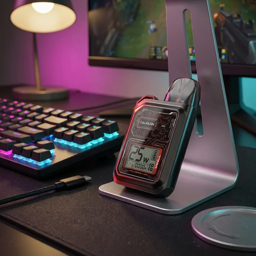 Uwell Caliburn GK3 sobre mesa gamer com teclado RGB e suporte de fone, luzes neon e reflexos - Vapor Gringo