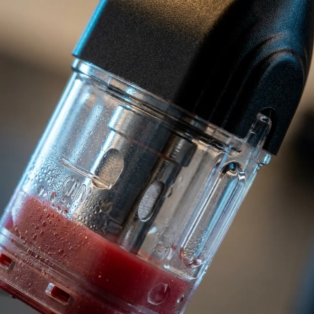 Close-up do pod Uwell KoKo Caliburn mostrando conector, bobina FeCrAl e gotas de condensação - Vapor Gringo