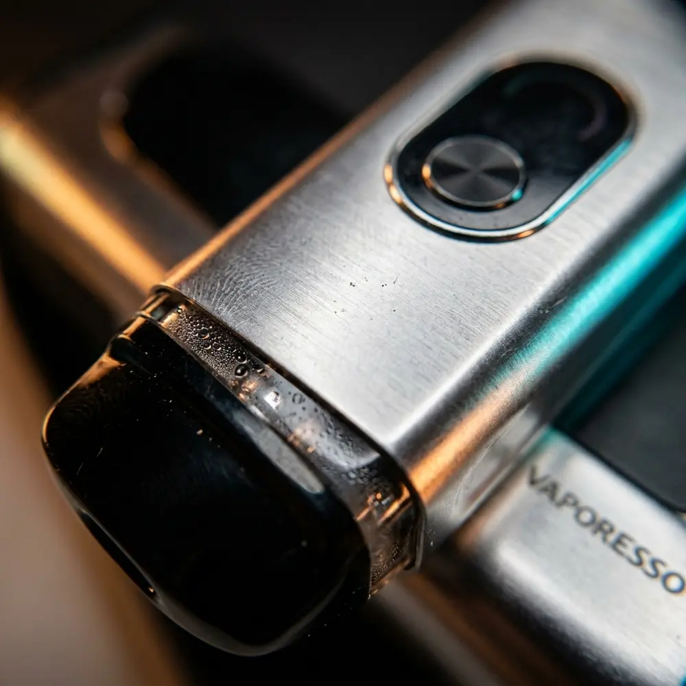 Detalhe do bocal e corpo em liga do Vaporesso XROS 4 com gotas de condensacao e reflexos metalicos - Vapor Gringo