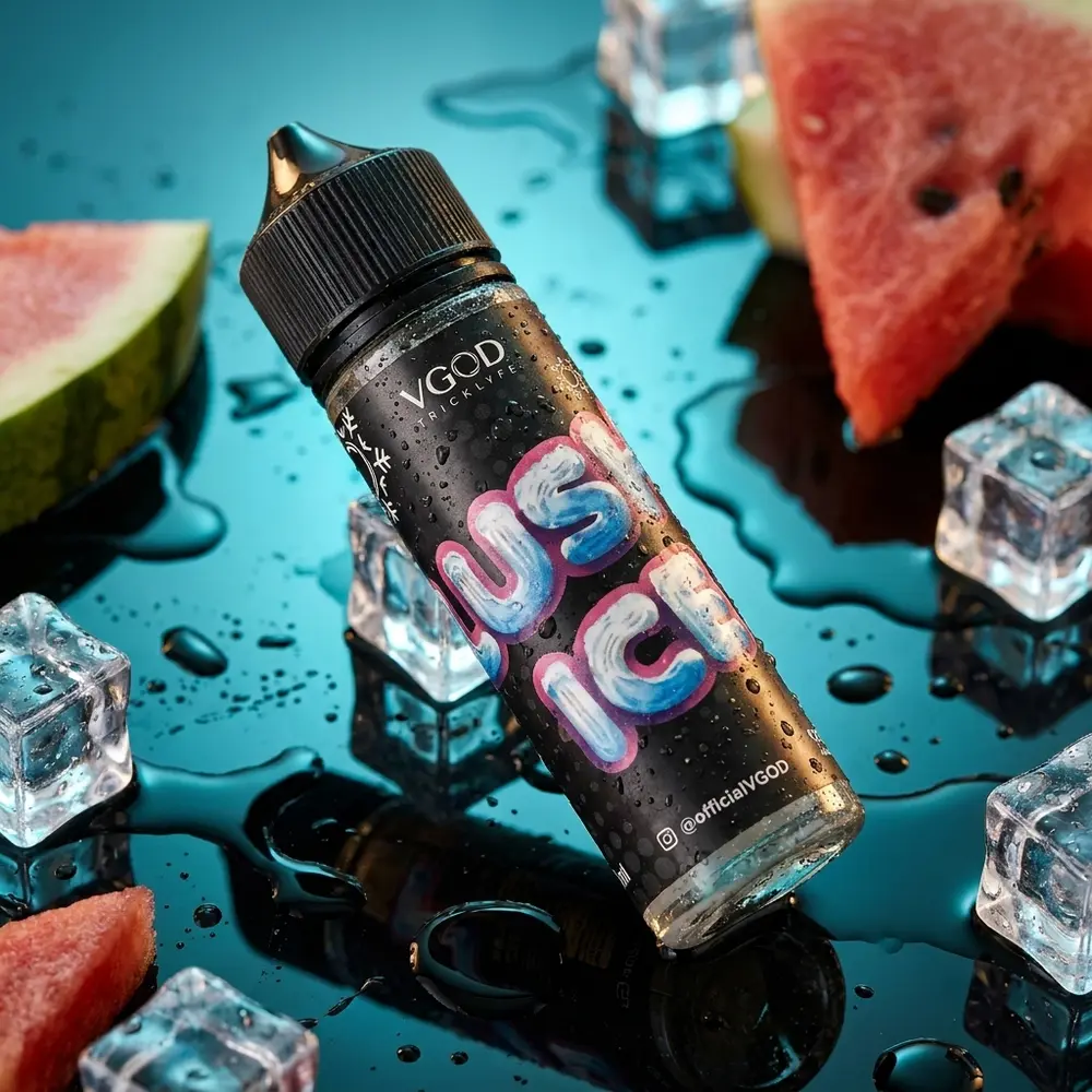 Frasco VGOD Lush Ice Ice Watermelon inclinado sobre acrilico molhado com fatia de melancia e gelo - Vapor Gringo