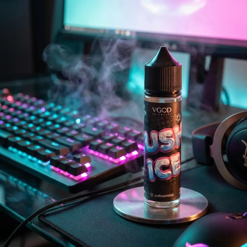 Frasco VGOD Lush Ice Ice Watermelon sobre mesa gamer RGB, teclado desfocado e vapor sutil ao fundo - Vapor Gringo