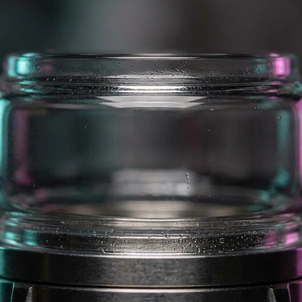 Detalhe macro do vidro Bubble Blotto RTA Dovpo mostrando curvatura Pyrex, gotas e reflexos precisos. - Vapor Gringo