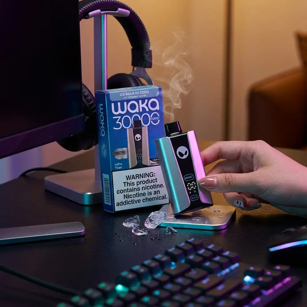 Pod Waka soPRO Titan Icy Coconut Water apoiado em mesa gamer com teclado RGB, fones e reflexos coloridos - Vapor Gringo