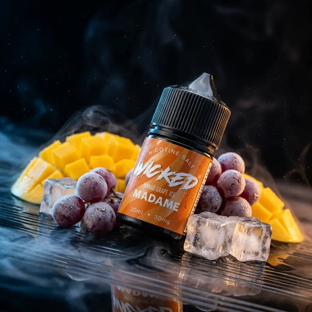 Frasco Wicked Salt Mango Grape Ice Madame sobre placa acrilica preta com gotas, manga, uvas e gelo. - Vapor Gringo