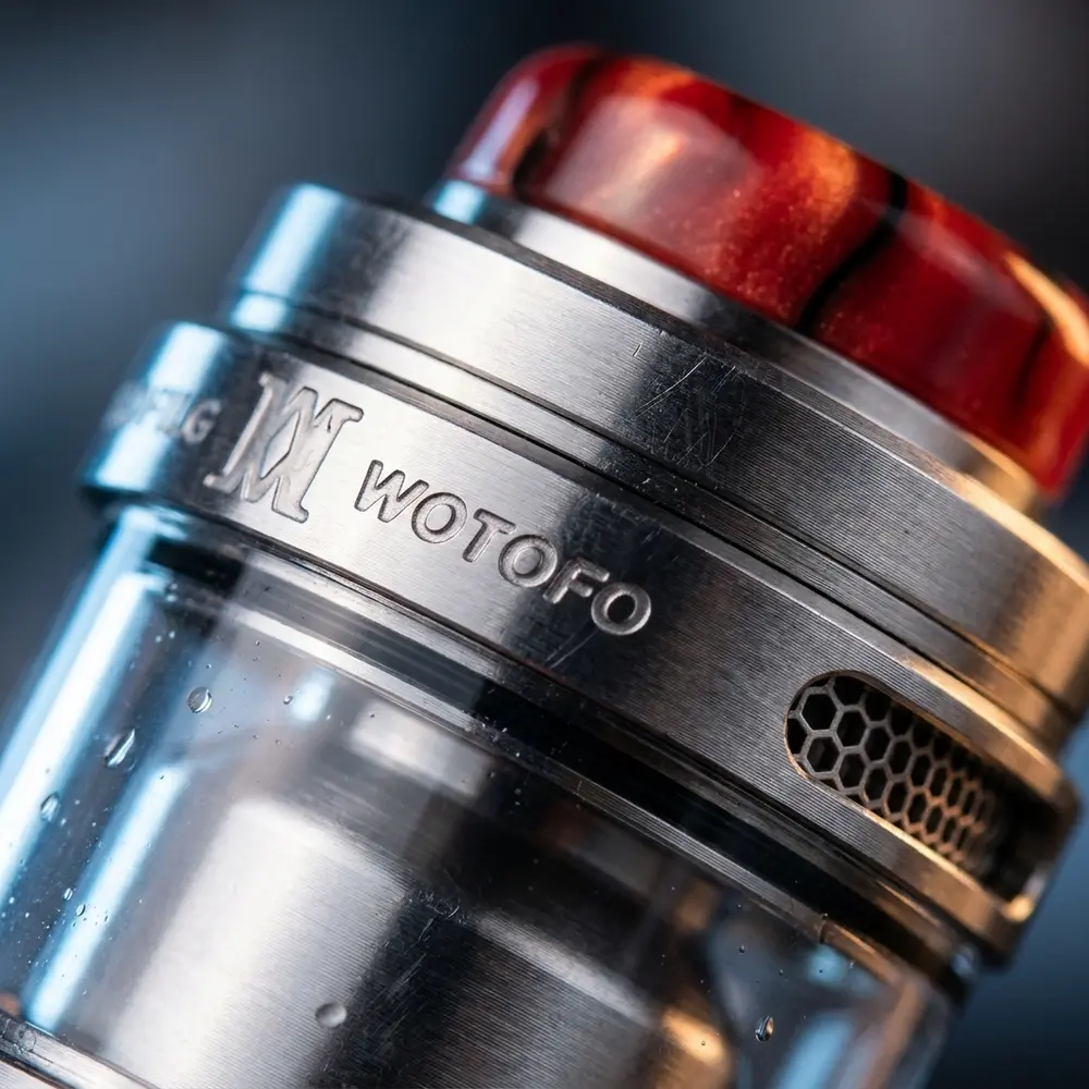 Macro do Wotofo Profile M RTA mostrando deck, fluxo em favo de mel, vidro bolha e gotas de condensacao - Vapor Gringo