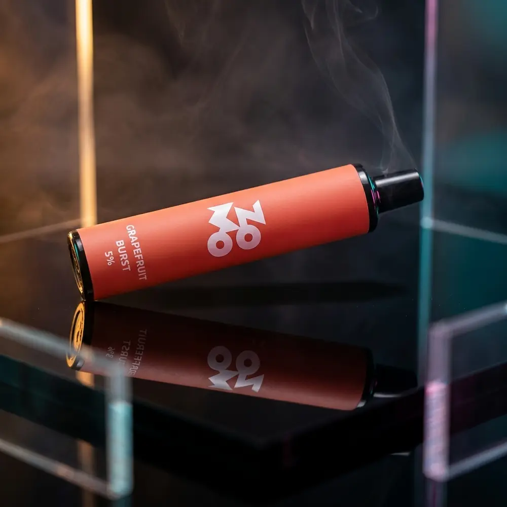 Pod descartável Zomo Flow Grapefruit Burst sobre base acrílica preta com luzes RGB e névoa suave - Vapor Gringo