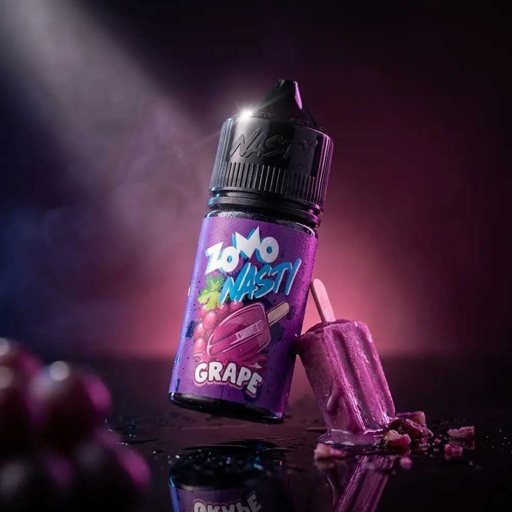 Garrafa Zomo Nasty Salt Grape Picolé inclinada sobre base acrílica com condensação e luzes roxas dramáticas - Vapor Gringo