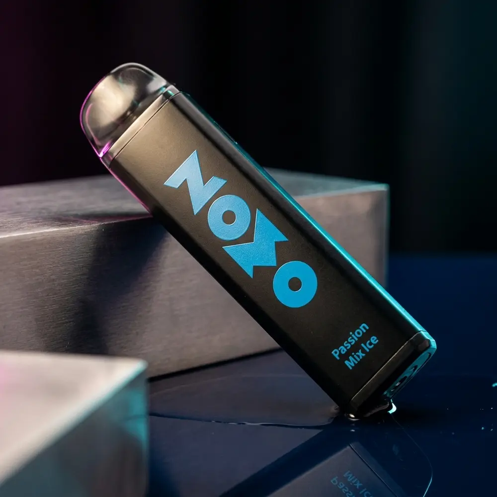 Pod descartavel Zomo Party Passion Mix Ice em close dramatico sobre acrilico azul com destaque no logo e reflexos noturnos - Vapor Gringo