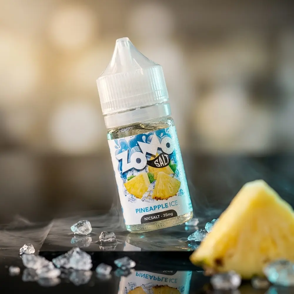Frasco Zomo Salt Pineapple Ice em close dramático sobre base acrílica com gelo e iluminação azul-citrus - Vapor Gringo